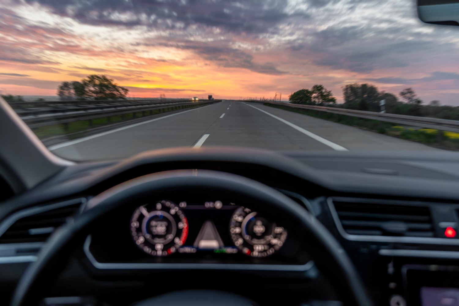 Open road seen from behind the wheel at sunset