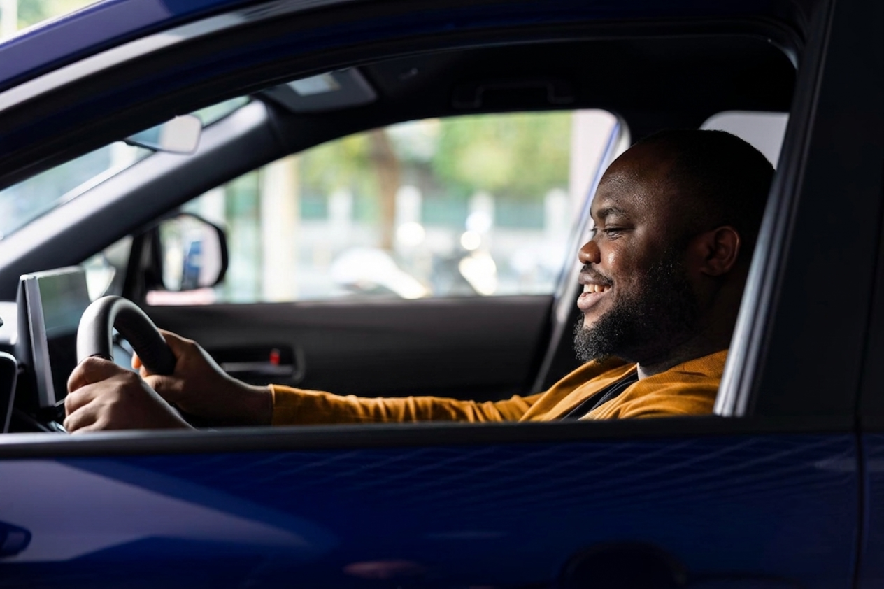 A confident driver smiling at the wheel of a car